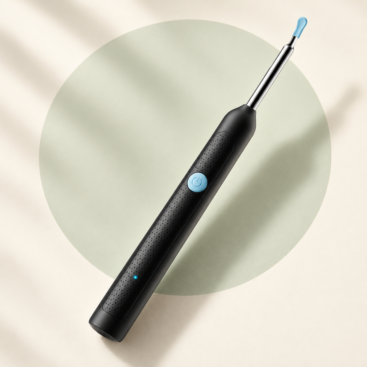 Black Y38 ear-camera device with blue fitted tip, blue power button and dotted handle on a cream and pale sage background